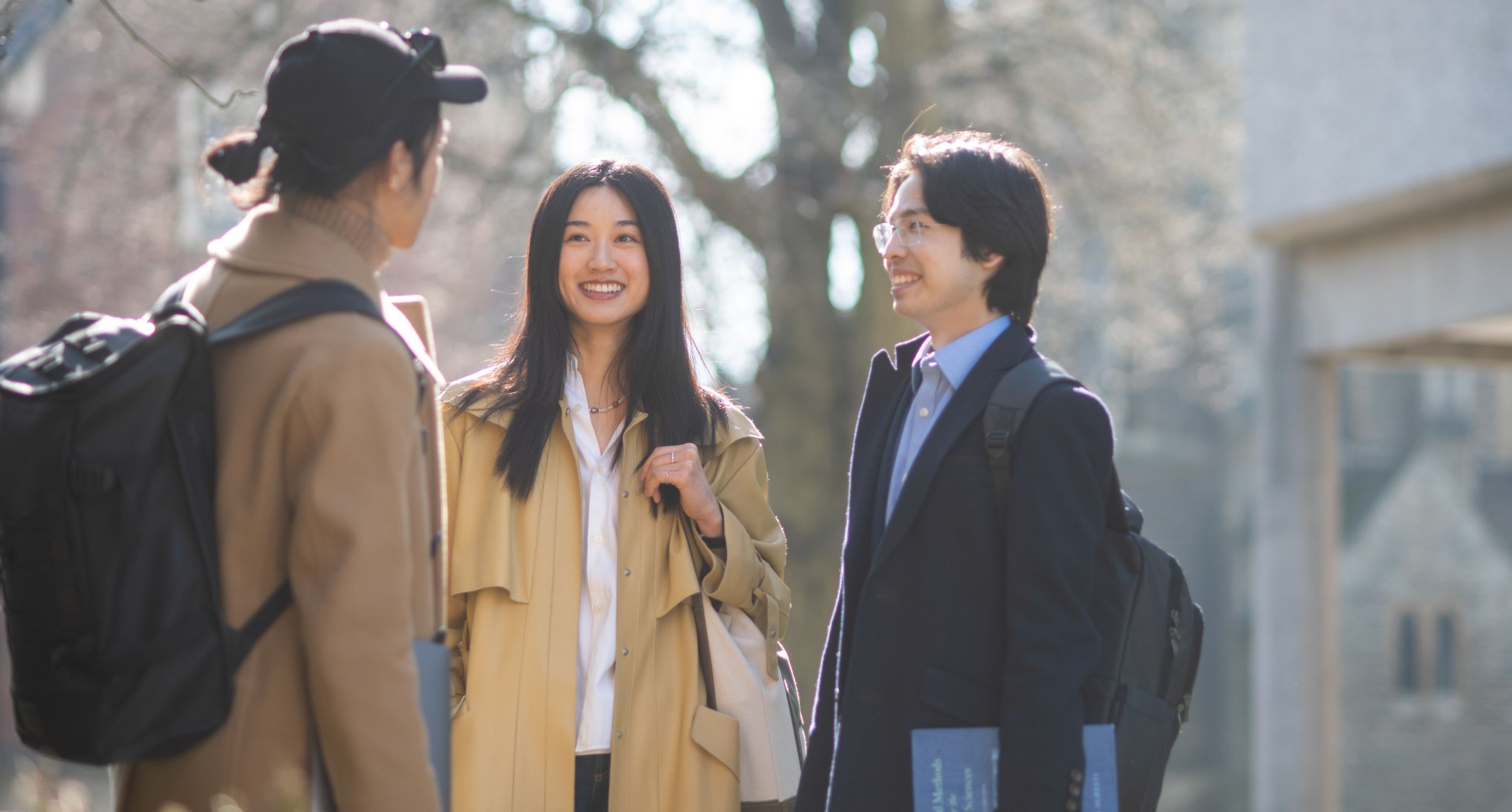 Three students standing outside chatting 