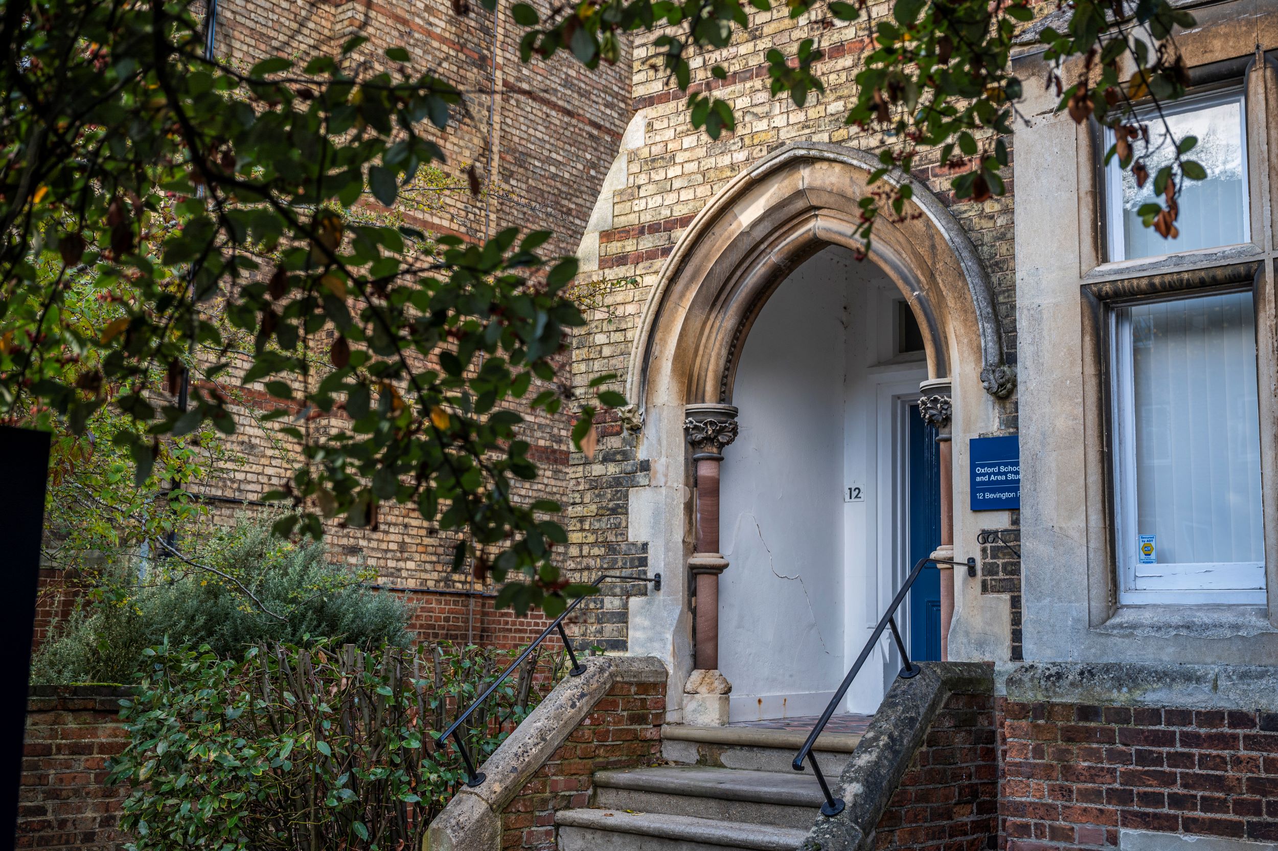 The front entrance to OSGA buildings, with an arched porchway surrounded by trees.