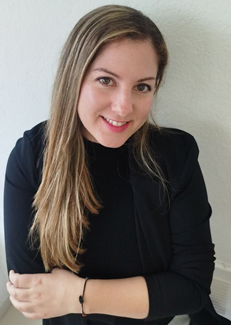 Belen has long dark blonde hair and is smiling at the camera. She is wearing a black jumper
