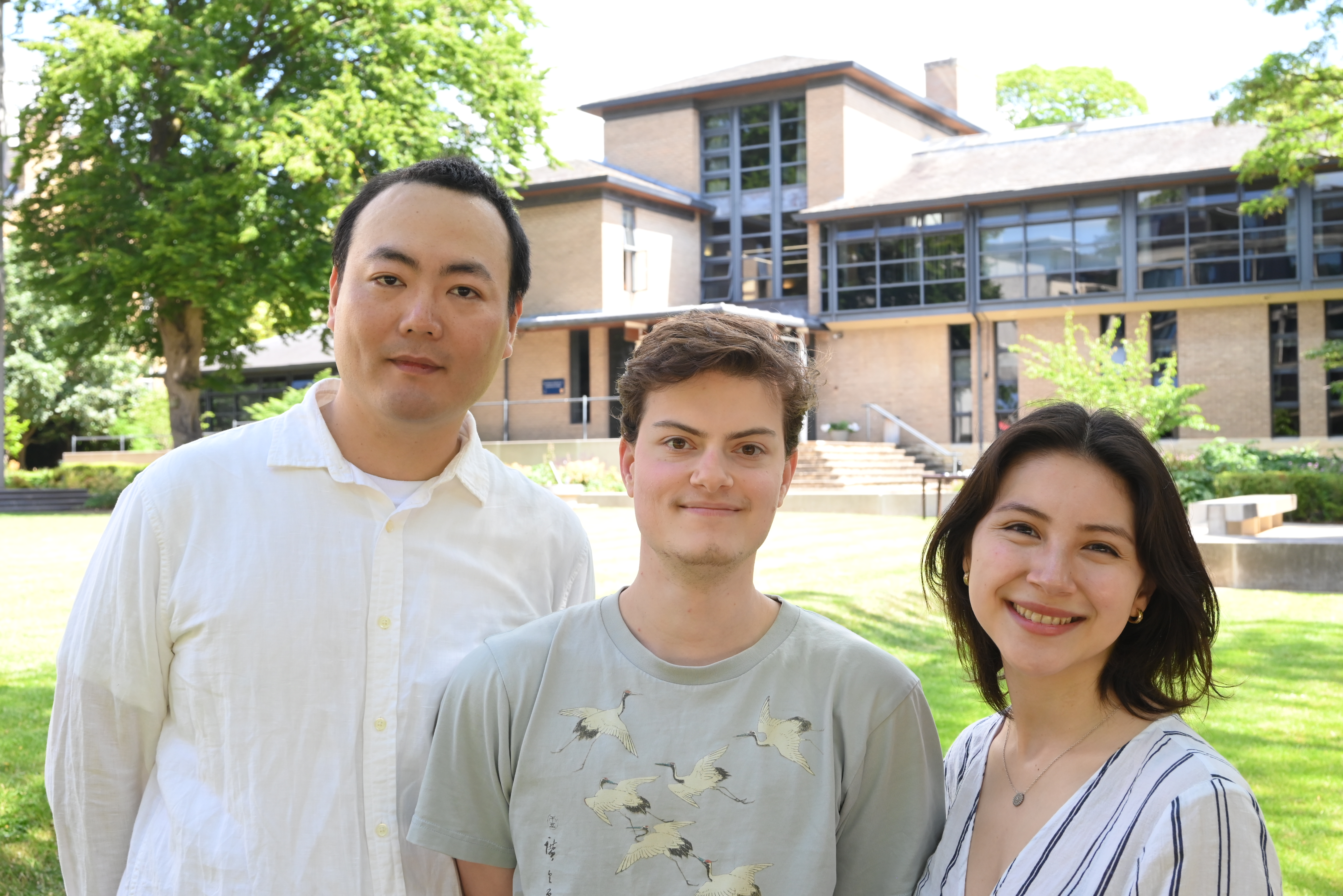 Three students standing in a garden outside an Oxford college building. 