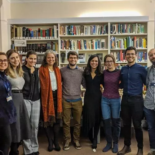 A group of people standing in front of large bookshelves, smiling. 2020