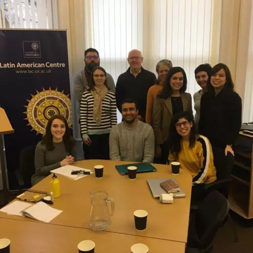 A group of people standing around a table, smiling. 2019