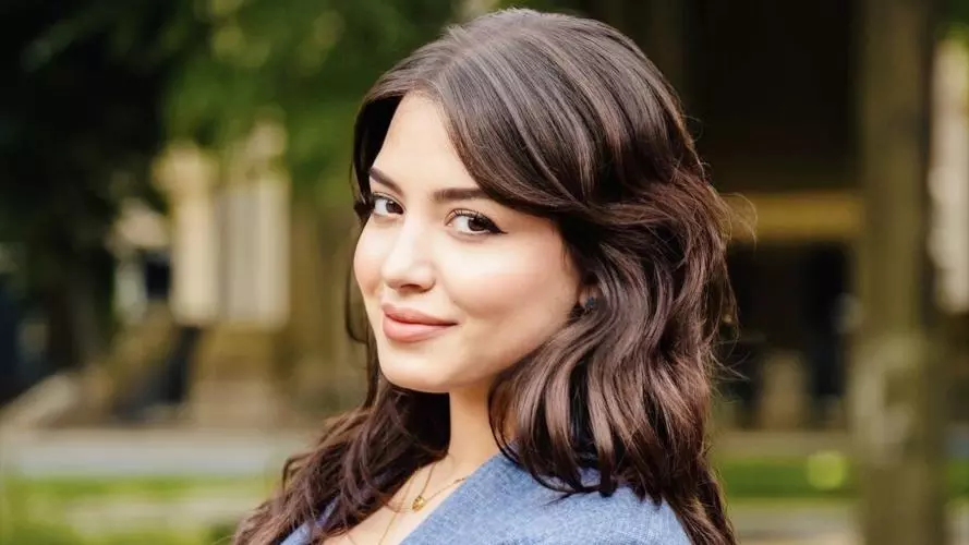 Assala Khettache has long brown hair and is wearing a blue jacket