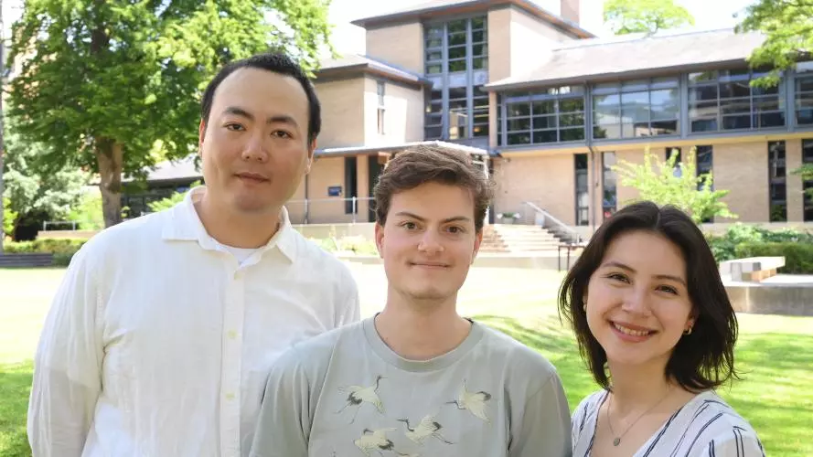 Three students standing in a garden outside an Oxford college building. 