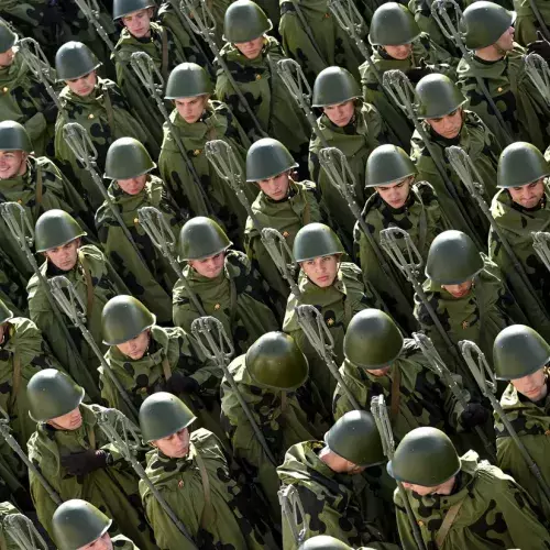An overhead shot of rows of around 30 soldiers in green camouflage uniforms, helmets and carrying equipment. 