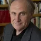William has short brown hair and is wearing a black shirt with dark grey jacket. There is a bookcase behind him. 