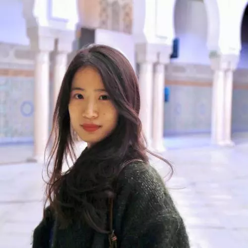 Dr Liu is standing side on, looking at the camera. She has long dark hair and is wearing an oversized dark green knitted cardigan.