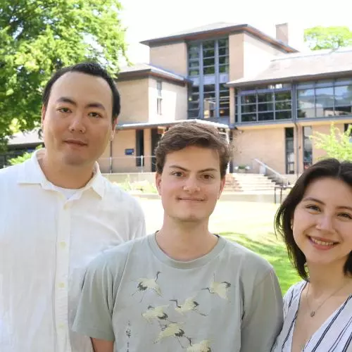 Three students standing in a garden outside an Oxford college building. 